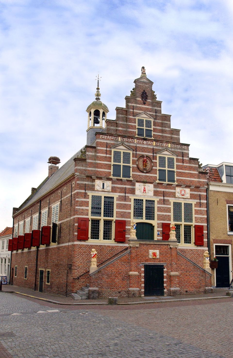 Historisch stadhuis en stadsmuseum Stadhuis, Oudewater, Groene Hart, karakteristiek bakstenen monument met trapgevel, rode luiken, bordestrappen en torentje aan het plein.