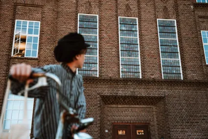 Loopjongen Rien op de fiets voor het gebouw van de KVl fabriek in het jaar 1954