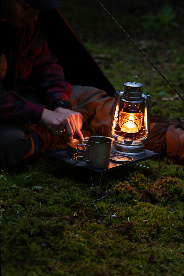 Eten voor de tent in het donker bij het sfeervolle licht van een olielampje.