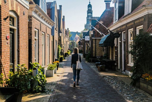 Een foto van een vrouw die op de Buren straat in Hindelopen in de zon loopt