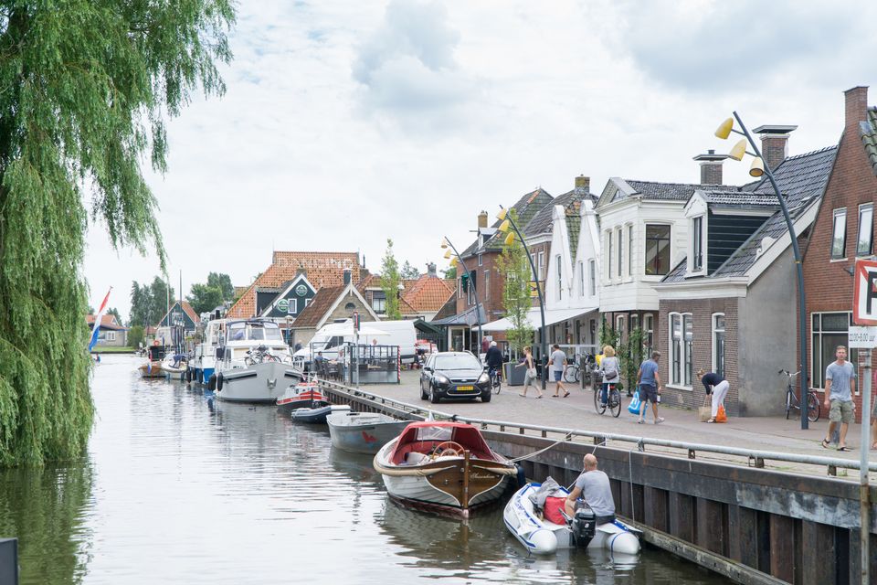 allemaal boten aan de oeverkant. naast de oever staan allemaal winkels