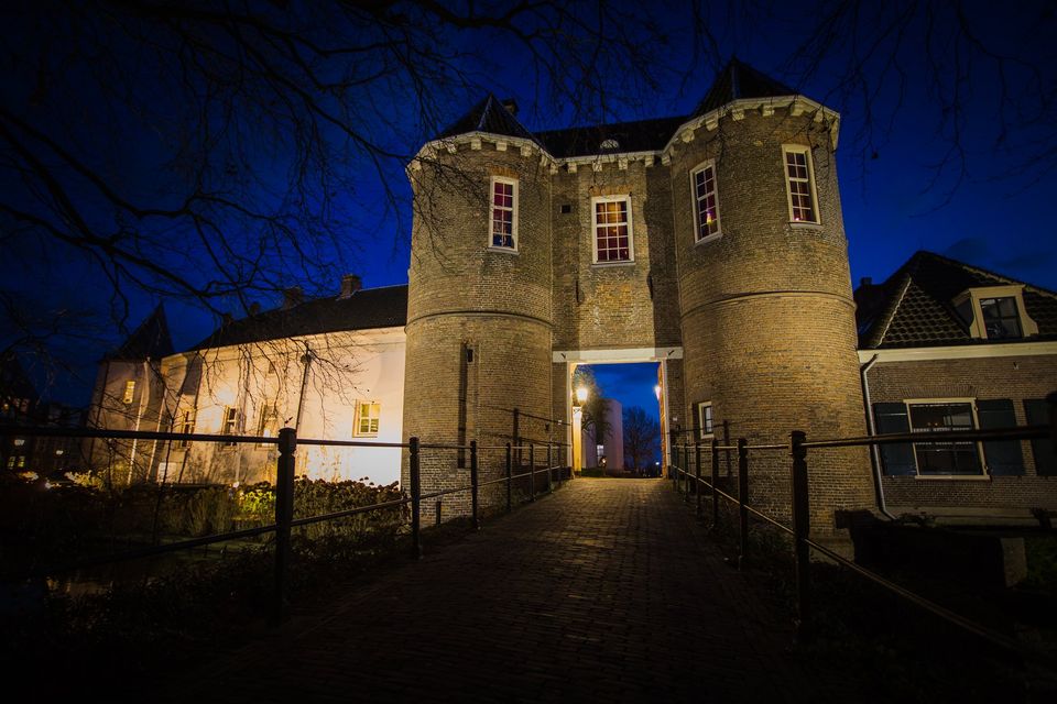 Kasteel Montfoort in de avond met verlichte toegangspoort en historische torens, sfeervol nachtbeeld van dit monumentale kasteel in Montfoort in het Groene Hart.