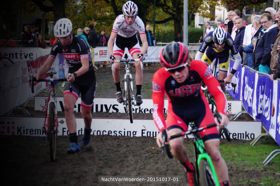 Wielercross tijdens de Nacht van Woerden in Woerden, Groene Hart. Wielrenners springen met hun cyclocrossfietsen over hindernissen op een modderig parcours, terwijl toeschouwers langs de kant de wedstrijd volgen.