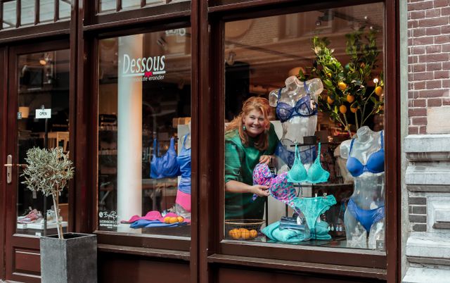 vooraanzicht van de lingerie zaak Dessous met een werkster achter het raam meet een lingerie top in haar hand.