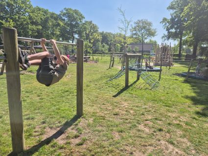 Jongetje aan duikelrek met op achtergrond de speeltuin van de Schaapjes