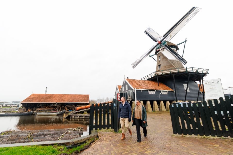 Twee mensen lopen weg bij Houtzaagmolen De Rat in IJlst bij regenachtig weer.