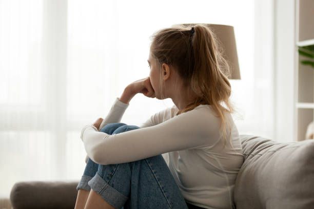 A woman sitting sad on the couch.