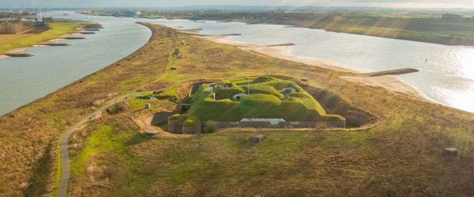 Een groot fort in de splitsing van twee rivieren, overgroeid met gras.