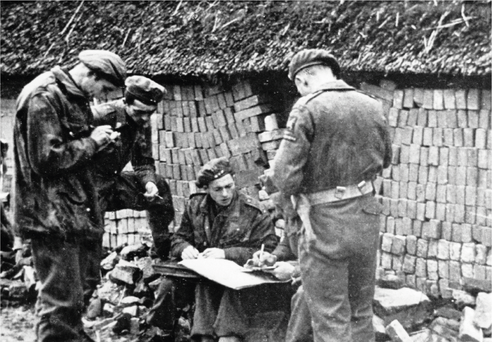 A British paratrooper (as seen from behind), who crossed the river, consults with Polish paratroopers.