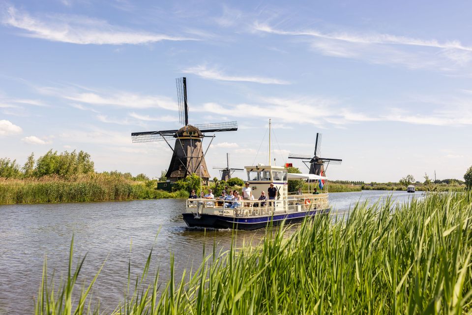 Rondvaart Kinderdijk, Alblasserdam, Zuid-Holland, Groene Hart, rondvaartboot vaart langs historische windmolens en rietkragen op UNESCO Werelderfgoed Kinderdijk tijdens een toeristische boottocht in het Groene Hart.