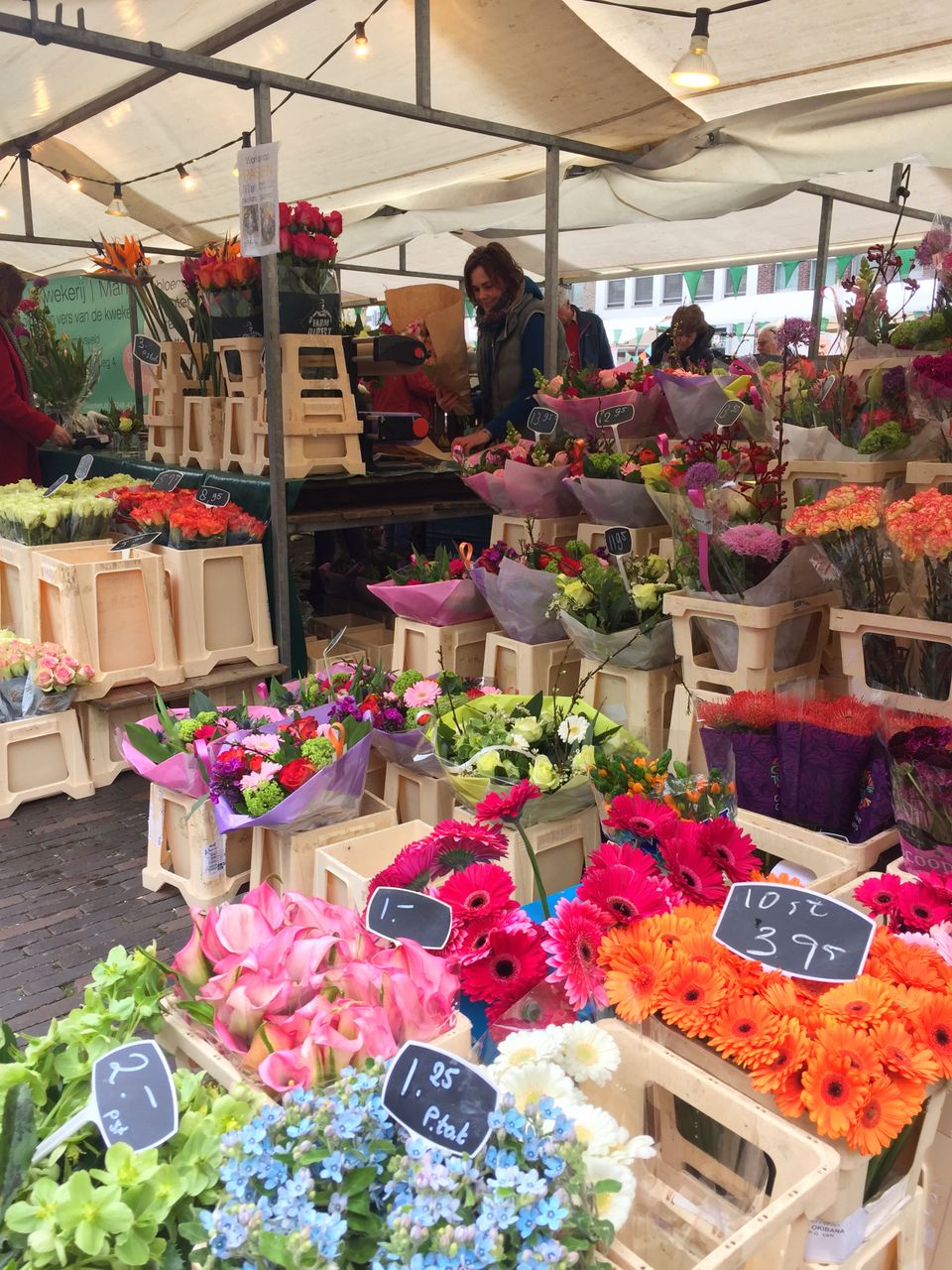 Kleurrijke bloemenkraam op de streekmarkt in Woerden met verse boeketten en planten onder een markttent.
