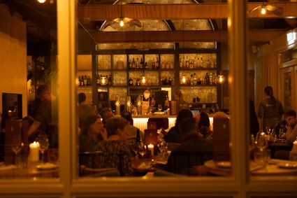 Restaurant Bistronoom in Woerden, Groene Hart, sfeervol restaurantinterieur met warme verlichting, volle tafels, gasten en een centraal gelegen bar.