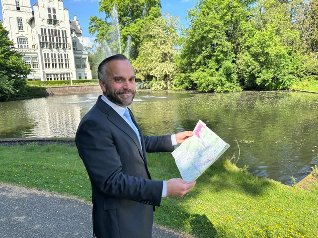 Wethouder Du Maine van de gemeente Vught houdt een plattegrond vast bij het Raadhuis, met op de achtergrond de vijver en fontein.
