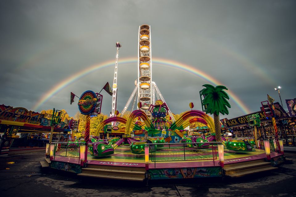 Koeiemart-kermis in Woerden, Groene Hart, met kleurrijke kermisattracties en een reuzenrad onder een dubbele regenboog. Foto: Joeri van Kemp.
