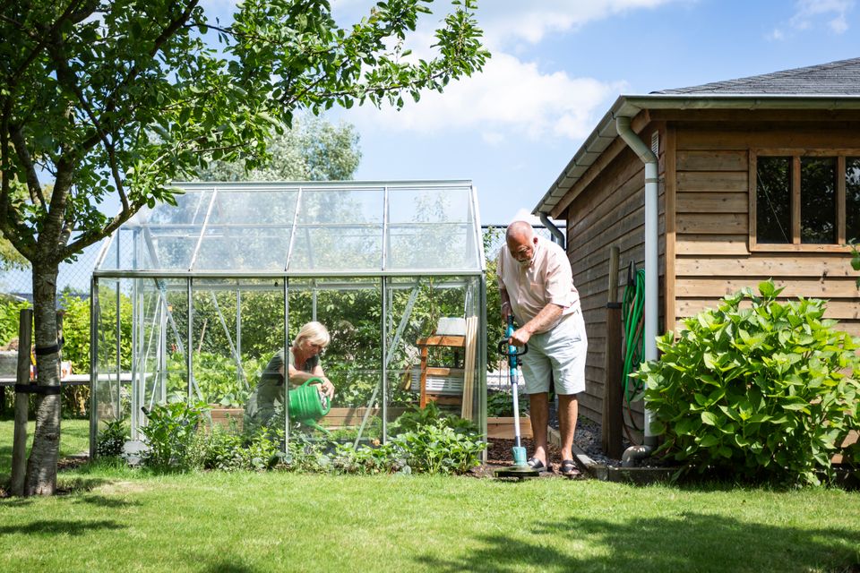 Een echtpaar tuiniert en maait het gras in de tuin bij hun woning in Lelystad, Flevoland