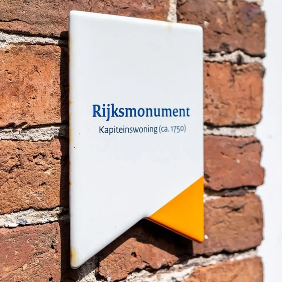 Een bordje met 'Rijksmonument Kapiteinswoning (ca.1750)' op de gevel van Silhûs in Woudsend.