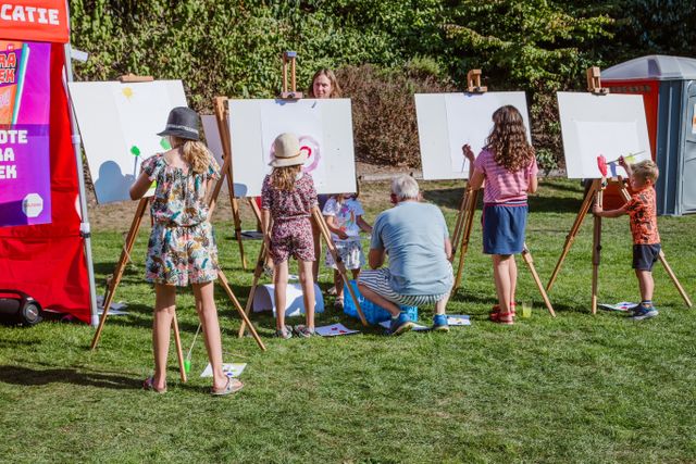 Kinderen achter schildersezels in het gras