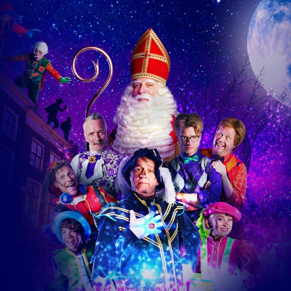 Sinterklaas en zijn pieten en de andere medespelers van de de film in kleurrijke kleding.