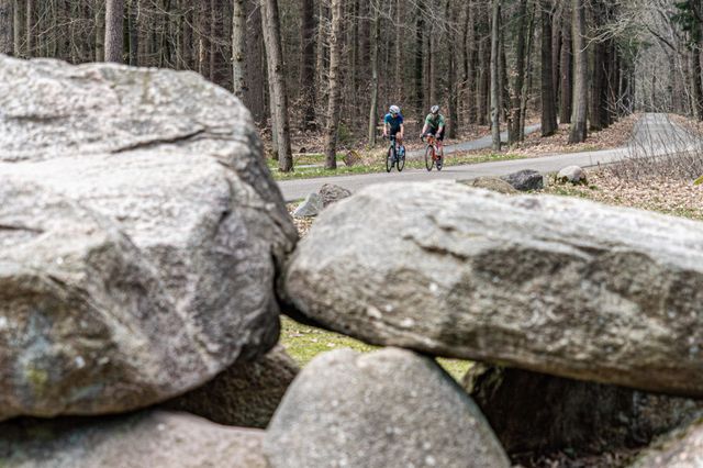 Wielrenners fietsen langs een hunebed in Drenthe.