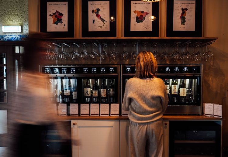 een vrouw tapt een glas uit een wijnbar