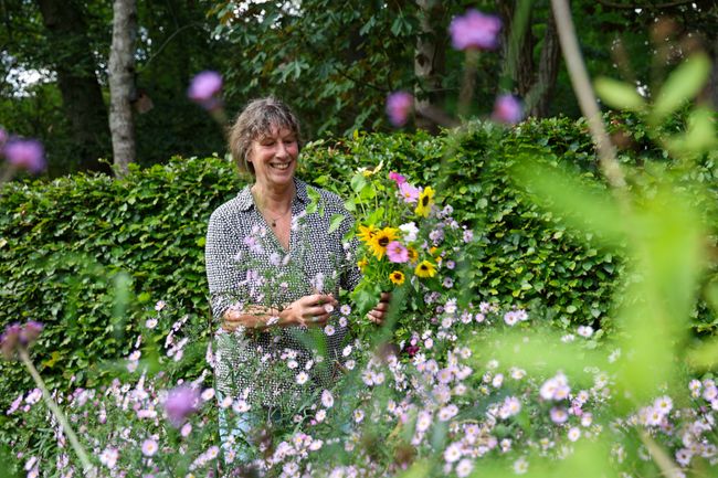 Een vrouw houdt een bosje vers geplukte bloemen vast.