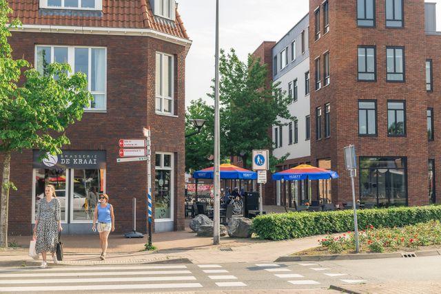 Straatbeeld in het centrum van Renswoude met Brasserie De Kraai, een terras en voorbijgangers bij een oversteekplaats. De foto toont de levendige en gastvrije sfeer van de dorpskern.