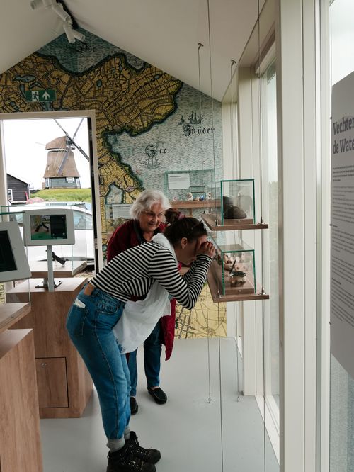 Een vrouw die door een verrekijker kijkt in het Archeologisch Minimuseum De Waterwolf