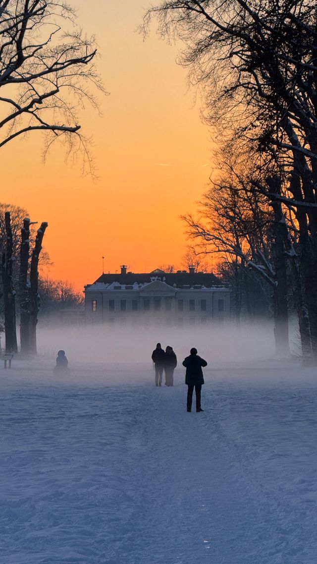 De lucht kleurt oranje door de ondergaande zon en Parc Broekhuizen is in sneeuw gehuld