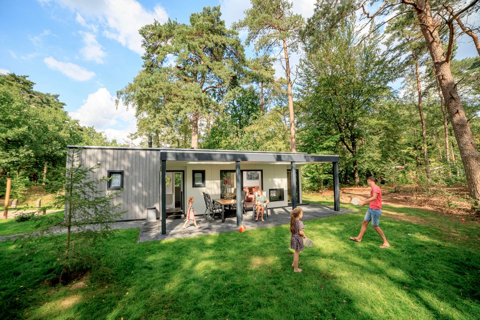 Vader en dochter spelen in de ruime tuin van chalet Zuylestein bij RCN het Grote Bos. Het moderne vakantiehuis ligt op een groene en bosrijke plek.