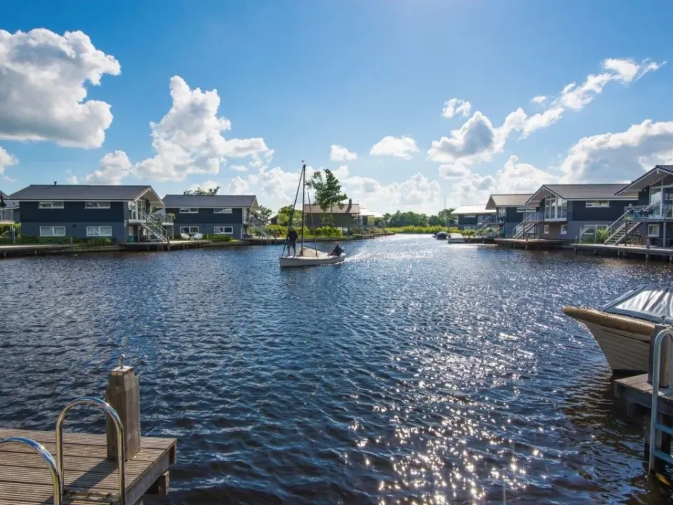Een zeilbootje op het water tussen de vakantiehuisjes bij Landal Waterpark Sneekermeer in Terherne.