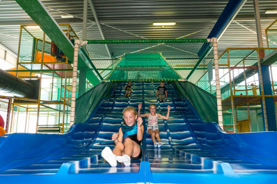 Kinderen glijden van glijbaan bij Speelbos Joure