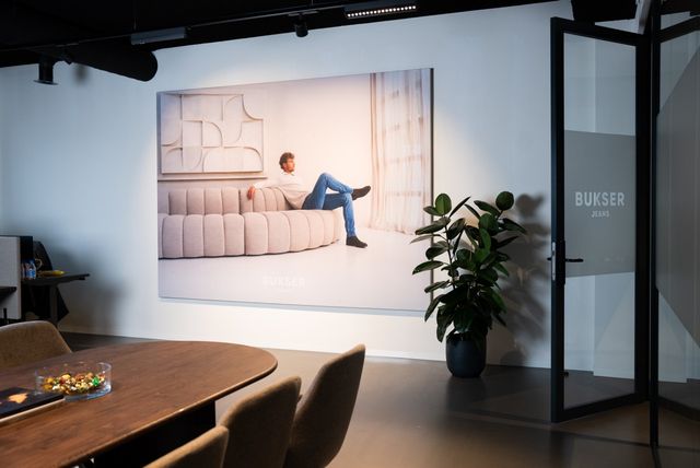 Jeanswinkel Busker Jeans in Woerden, Groene Hart, interieur met groot campagnebeeld van jeansmode aan de wand en zicht op de winkelruimte.