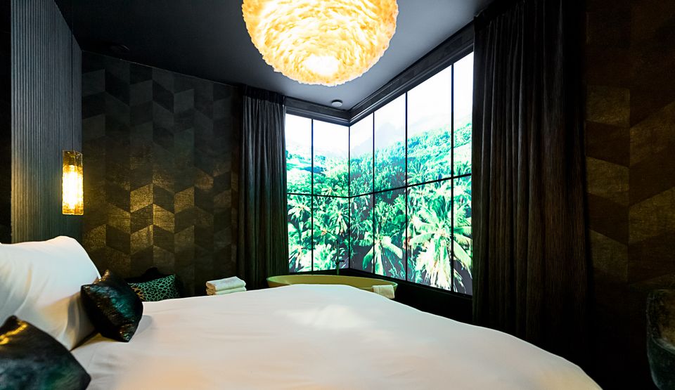 Chique, donkere hotelkamer met kingsize bed.