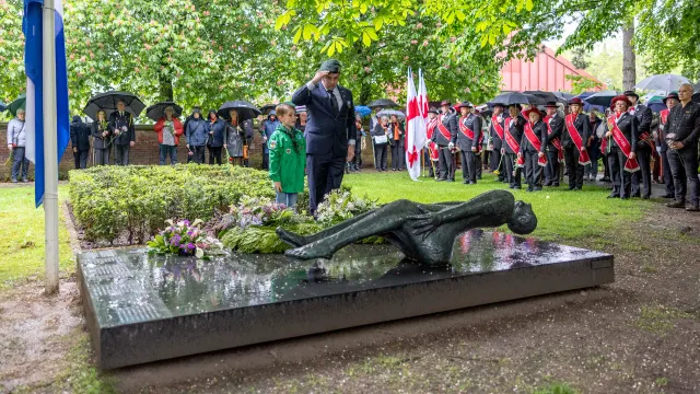 een militair brengt een saluut bij de kranslegging bij het beeld van de gevallen mens