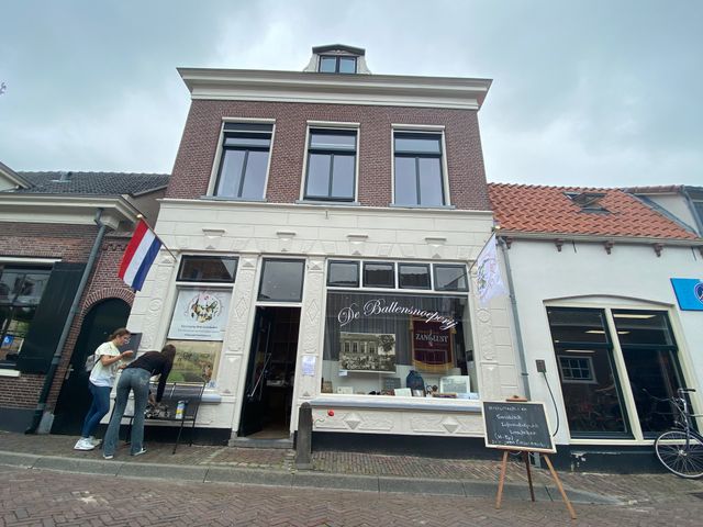Voorgevel van De Ballensnoeperij in Linschoten, met historische uitstraling, vlaggen en bezoekers voor de ingang van Vereniging Oud Linschoten.