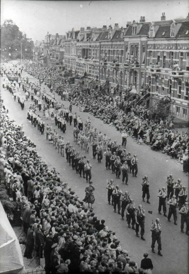 Twee detachementen Nederlandse militairen op het parcours van 40 km (gevolgd door een burgergroep) en enkele groepen overheidspersoneel op het parcours van 50 km defileren, gade geslagen door rijen dik toeschouwers en geflankeerd door enige individuele wandelaars, bij de intocht op de vierde dag van een Vierdaagse.