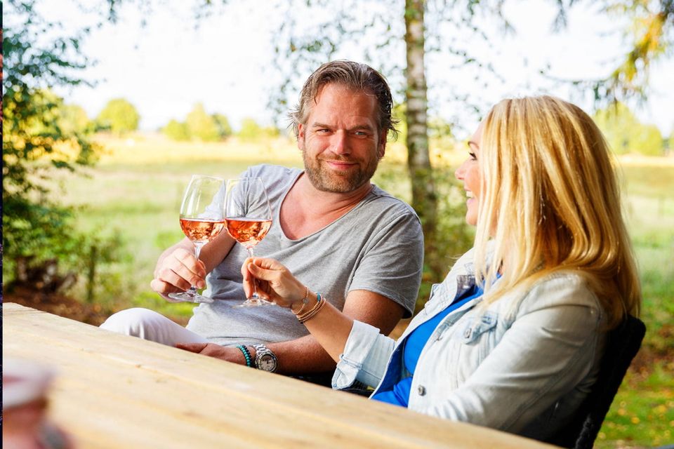 Mann und Frau stoßen draußen mit einem Glas Wein an