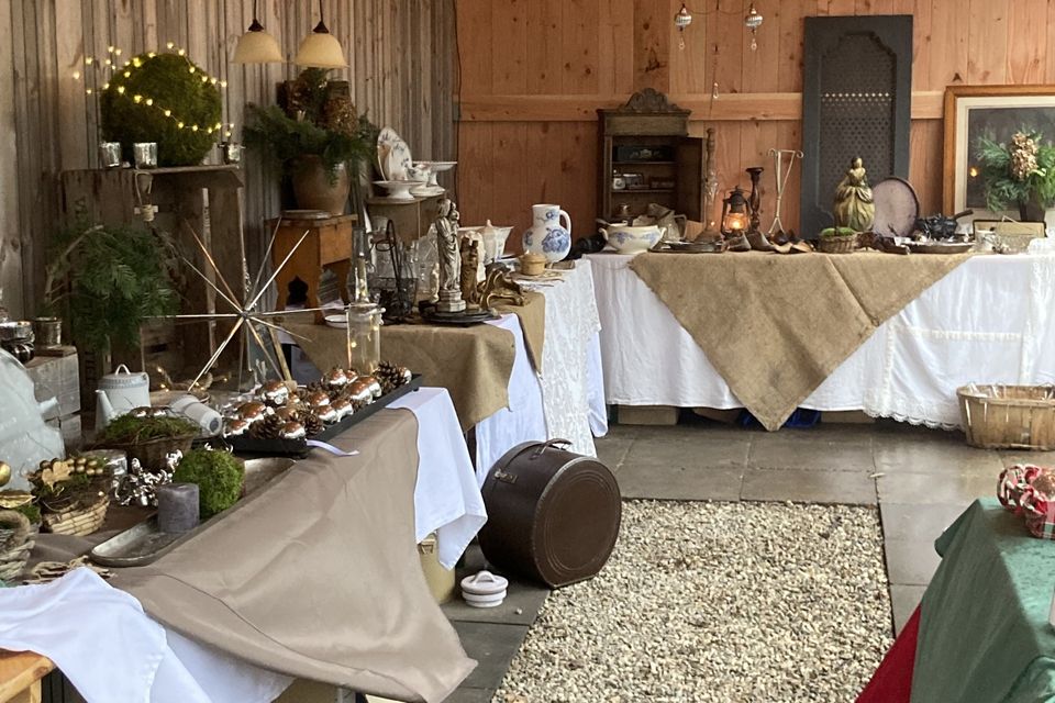 Een sfeervolle ruimte met tafels, bekleed met witte kleden en daarop diverse kerst-items tentoongesteld voor de kerstmarkt Linschoten.