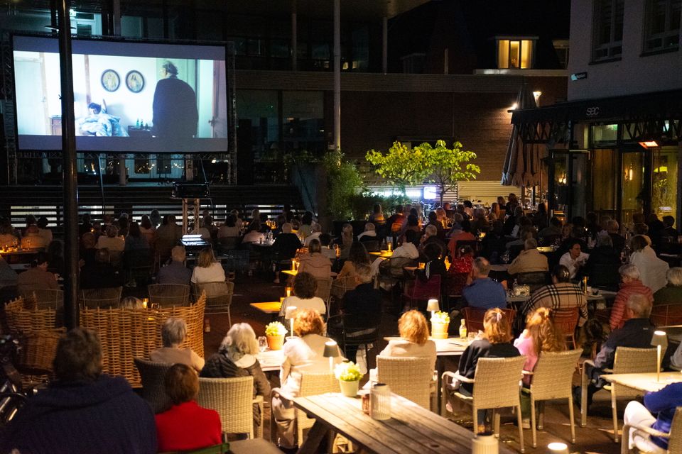 Lindeplein in Oisterwijk in het donker vol met mensen die film kijken