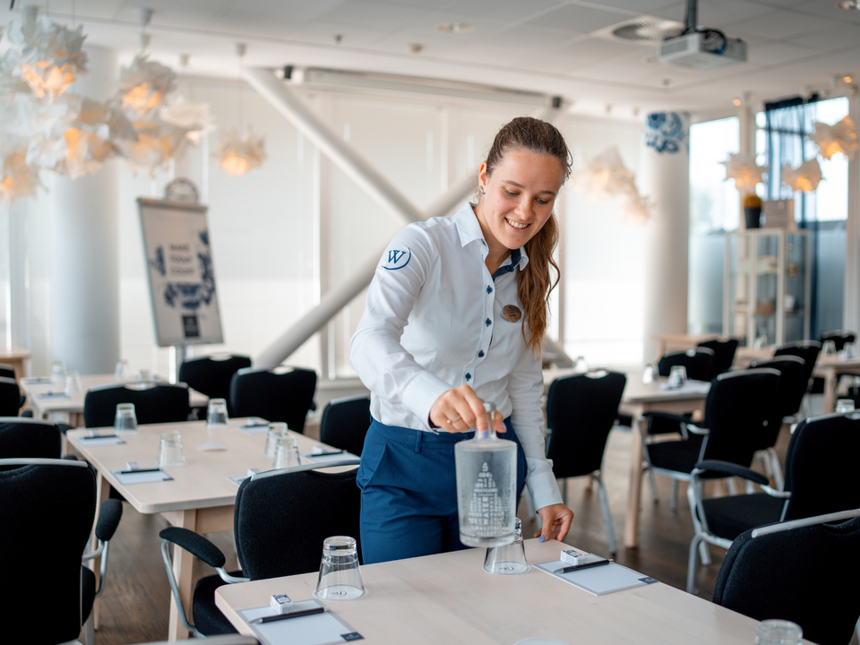 UITvergroot een serveerster die water neerzet op een tafel bij Westcord Hotel Delft