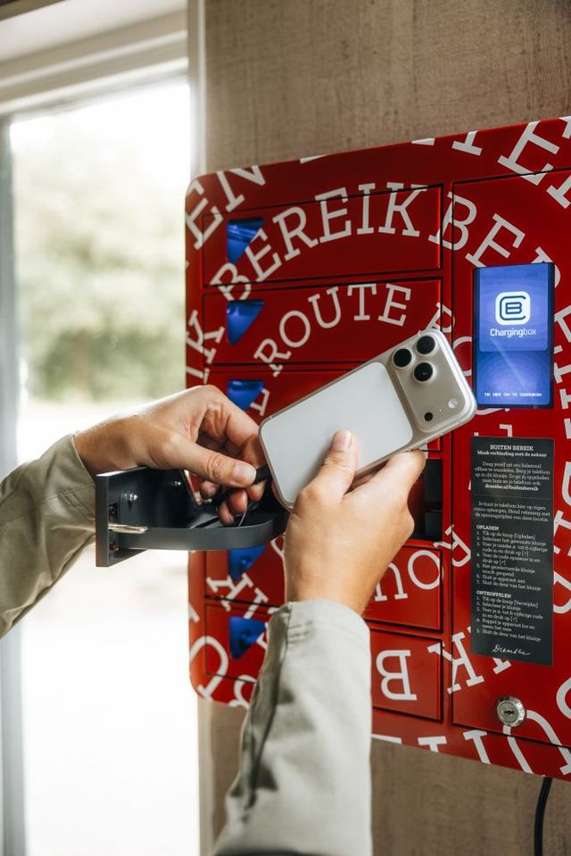 Een man laadt zijn telefoon op in een telefoonkluisje.