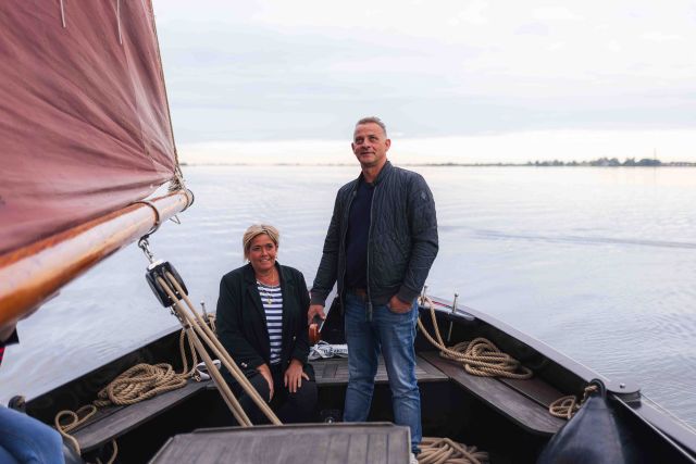 Twee mensen waarvan een aan het roer op de Lemsteraak van Brette Hoanne.