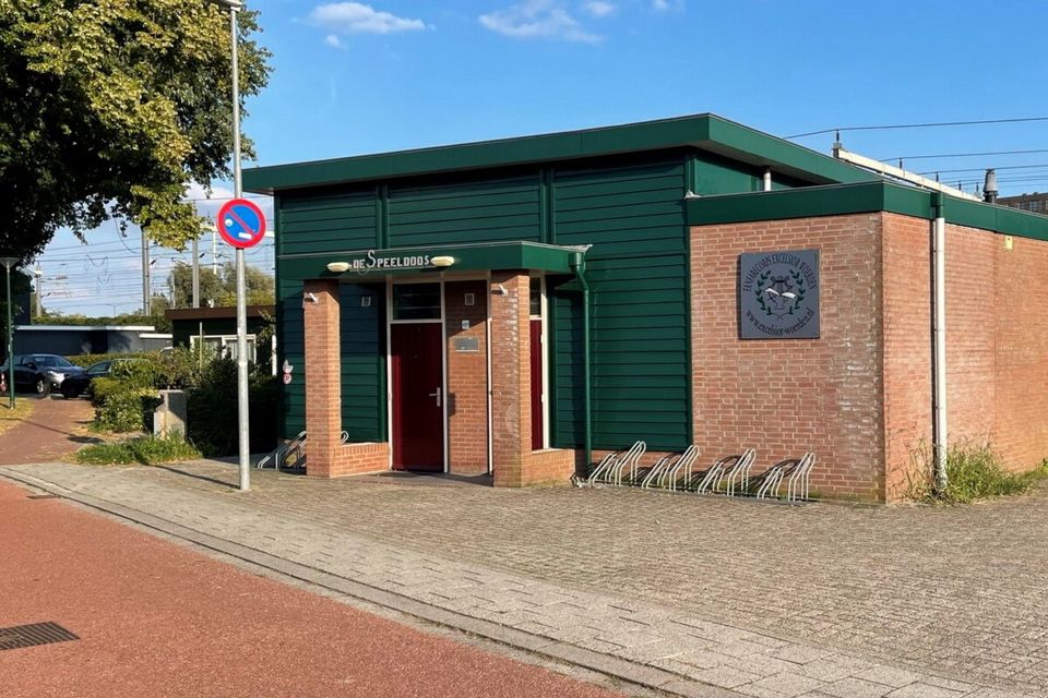 Clubgebouw De Speeldoos van Koninklijke Excelsior Woerden in Woerden, Groene Hart, exterieur van het verenigingsgebouw van de muziekvereniging met herkenbare groene gevel, entree en fietsenrekken langs de straat.
