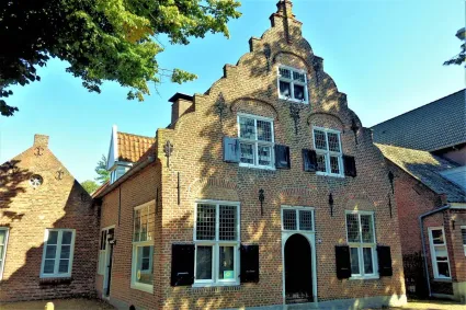 Monumentaal pand  met een zogenaamde gezwenkte trapgevel en ramen met oude luiken.