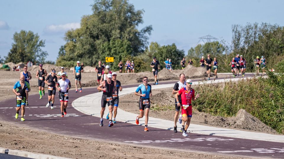 Hardlopers lopen hard op een fietspad tijdens de Challenge Almere-Amsterdam in Flevoland