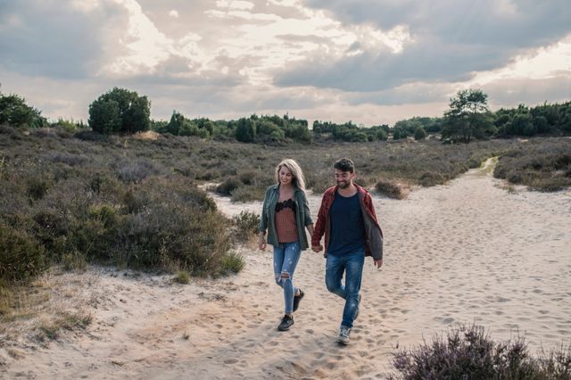 Man en vrouw wandelen hand in hand over de hei.