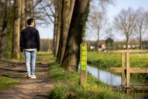 Een wandelaar bij een routepaal met daarop een Van Gogh routebordje.