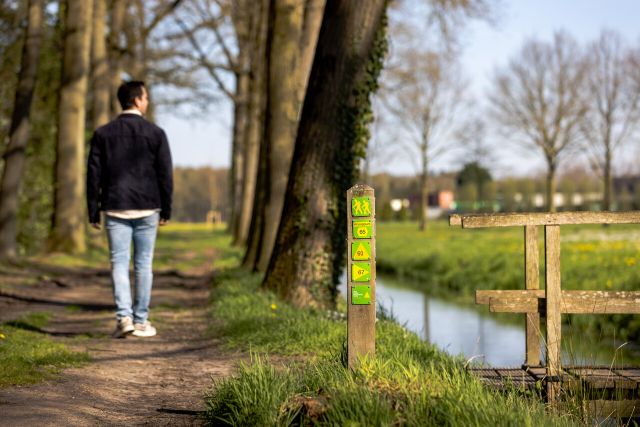 Een wandelaar bij een routepaal met daarop een Van Gogh routebordje.