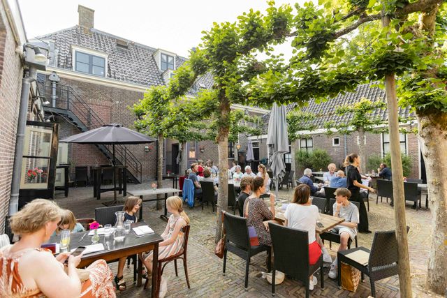 De binnenplaats van het Het Broeker Huis gevuld met mensen op het terras