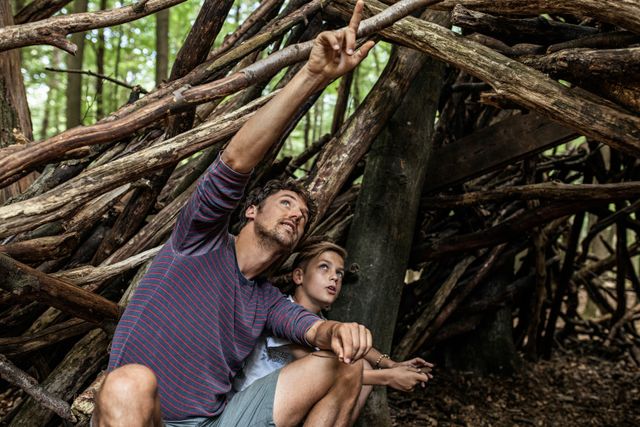 Vader en zoon bij een stapel takken in het bos in Drenthe.